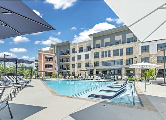 A large swimming pool is surrounded by sun loungers and umbrellas at Luxe 360 on Centerpointe Apartments, Virginia