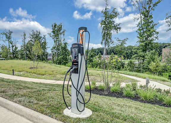 An electric vehicle charging station is on a concrete pad in a grassy area at Luxe 360 Apartment Complex in Midlothian Virginia