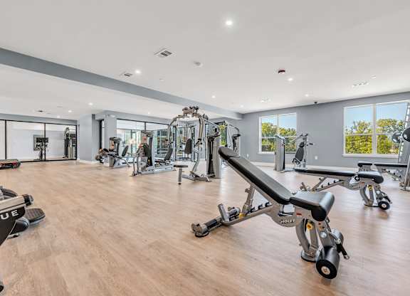A gym with a variety of equipment including a bench press at Luxe 360 on Centerpointe Apartments, Midlothian, VA, 23114