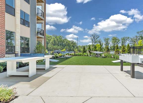 A sunny day at a residential complex with a white bench and a concrete path at Luxe 360 on Centerpointe Apartments, Midlothian, 23114