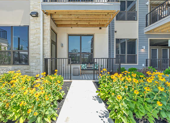 A building with a wooden entrance and a white walkway in front at Luxe 360 on Centerpointe Apartments, Midlothian, VA