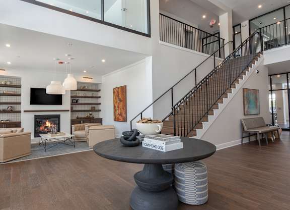 A living room with a fireplace and a staircase at Luxe 360 on Centerpointe Apartments, Midlothian, VA, 23114