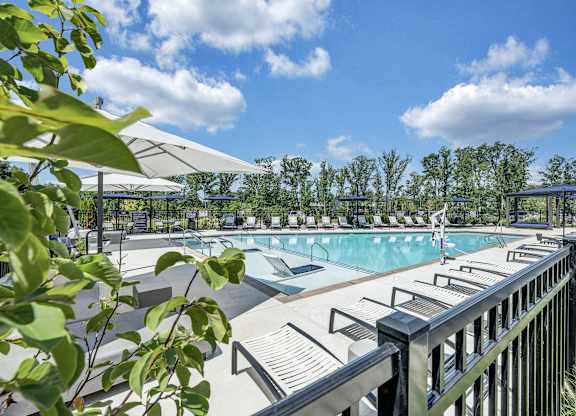 A pool area with sun shades and a metal fence at Luxe 360 Apartment Complex in Midlothian Virginia