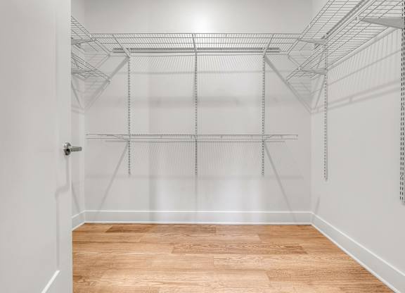 Empty walk-in closet with shelves and a wooden floor at Luxe 360 on Centerpointe Apartments, Midlothian, Virginia