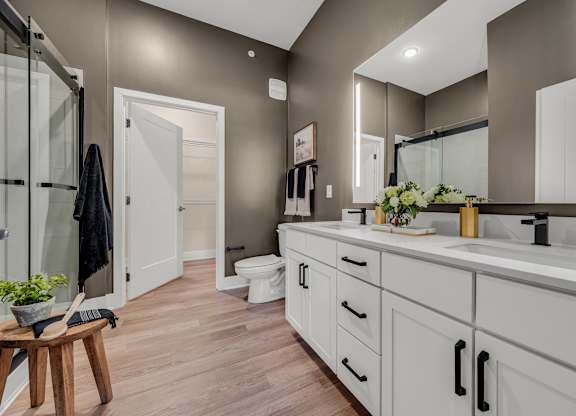 A bathroom with a toilet, sink, and mirror at Luxe 360 on Centerpointe Apartments, Virginia