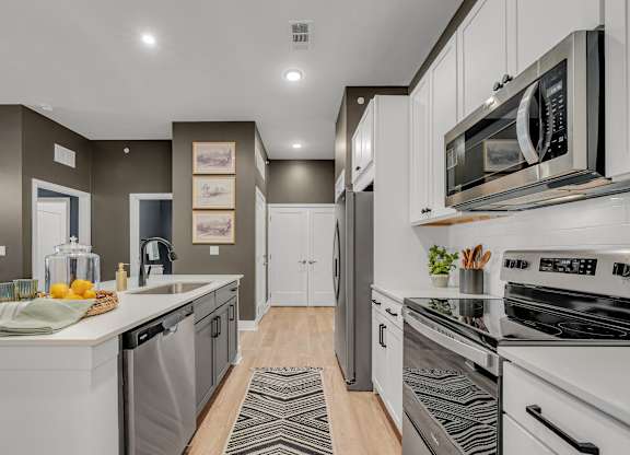 A modern kitchen with white appliances and a wooden floor at Luxe 360 on Centerpointe Apartments, Midlothian, VA
