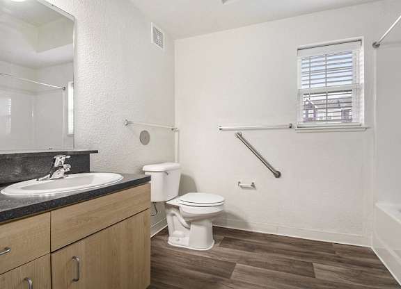 A bathroom with a toilet, sink, and a window at Lynbrook Apartments and Townhomes, Elkhorn, NE, 68022