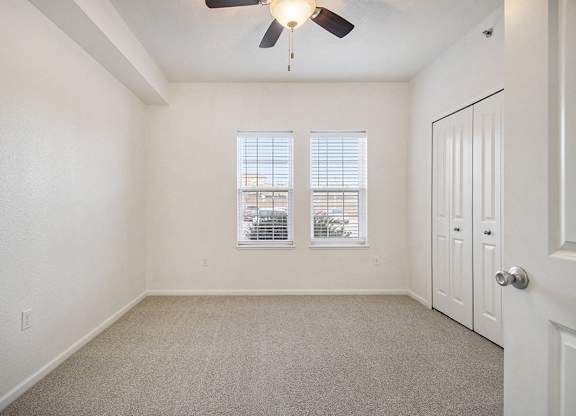 A bedroom with a ceiling fan and two windows at Lynbrook Apartments and Townhomes, Elkhorn, NE, 68022