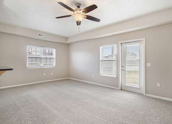 An end style living room with a ceiling fan and windows at Lynbrook Apartments and Townhomes, Elkhorn, NE, 68022
