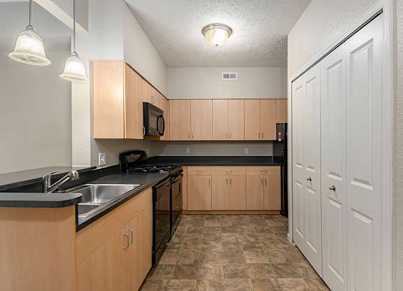 A kitchen with black countertops and wooden cabinets at Lynbrook Apartments and Townhomes, Elkhorn, NE, 68022