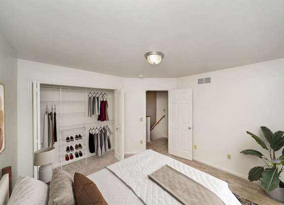 A bedroom with a bed, and a closet with organizers at Lynbrook Apartment Homes and Townhomes, Elkhorn