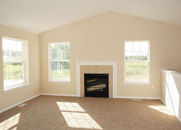 A living room with a fireplace and windows at Lynbrook Apartment Homes and Townhomes, Elkhorn