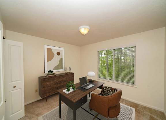 A bedroom with a brown desk with a laptop and a chair at Lynbrook Apartment Homes and Townhomes, Elkhorn