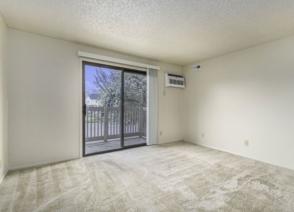 an empty living room with a sliding glass door to a balcony at Madeira Apartments, Kalamazoo, 49001