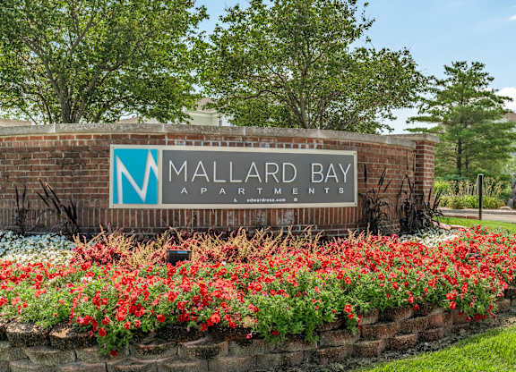 A sign for Mallard Bay Apartments is surrounded by flowers at Mallard Bay Apartments, Crown Point, Indiana
