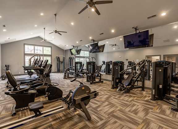 A spacious gym with a variety of equipment including treadmills, stationary bikes, and weight machines at Mallard Bay Apartments, Crown Point, Indiana