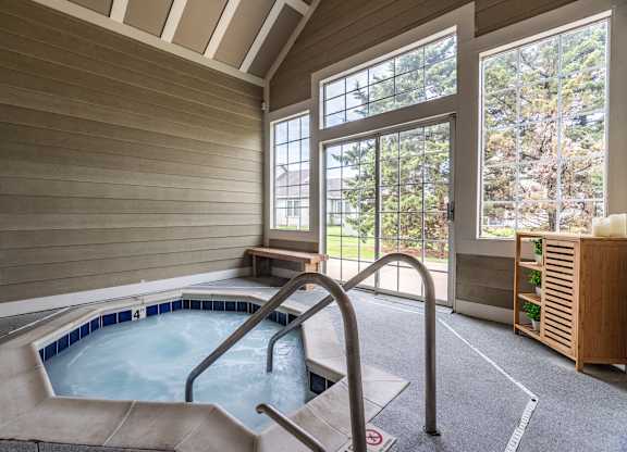 A hot tub in a room with a window overlooking a forest at Mallard Bay Apartments, Crown Point, Indiana