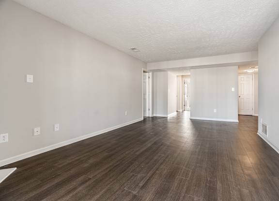 A large empty room with wooden flooring and white walls at Mallard Bay Apartments, Crown Point, Indiana