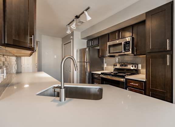 A modern kitchen with dark brown cabinets and a white countertop at Mallard Bay Apartments, Crown Point, Indiana