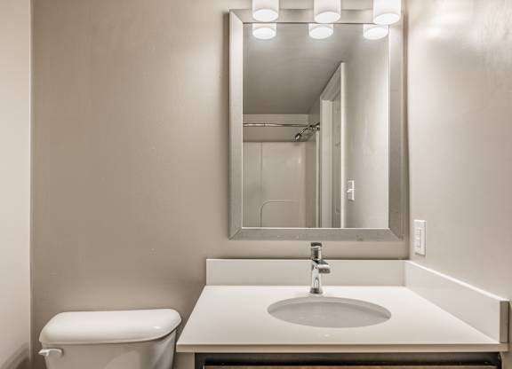 A bathroom with a toilet, sink and mirror at Mallard Bay Apartments, Crown Point, Indiana