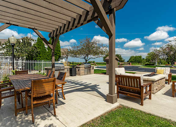 A wooden patio with a table and chairs under a pergola at Mallard Bay Apartments, Crown Point, Indiana