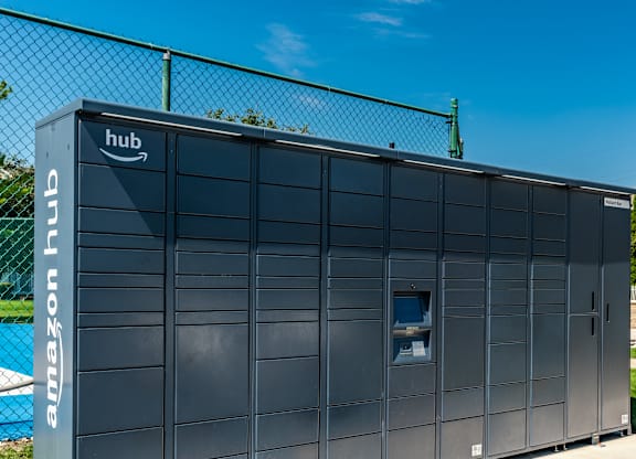 A large Amazon hub building is shown with a fence in the background at Mallard Bay Apartments, Crown Point, Indiana