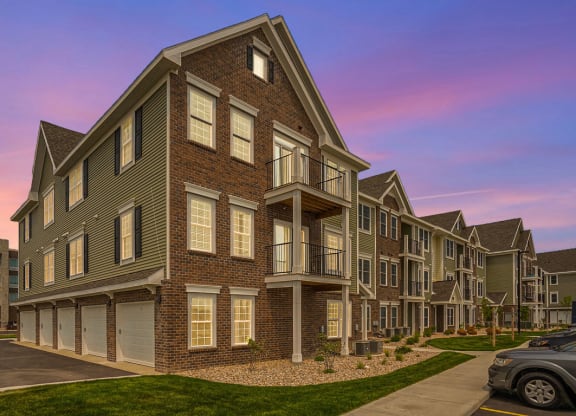 an exterior view of an apartment complex with a sunset in the background at Meadowbrooke Apartment Homes, Grand Rapids, Michigan