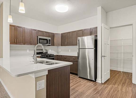 A kitchen with a breakfast bar and a stainless steel refrigerator at Meadowbrooke Apartment Homes in Grand Rapids, MI 49512