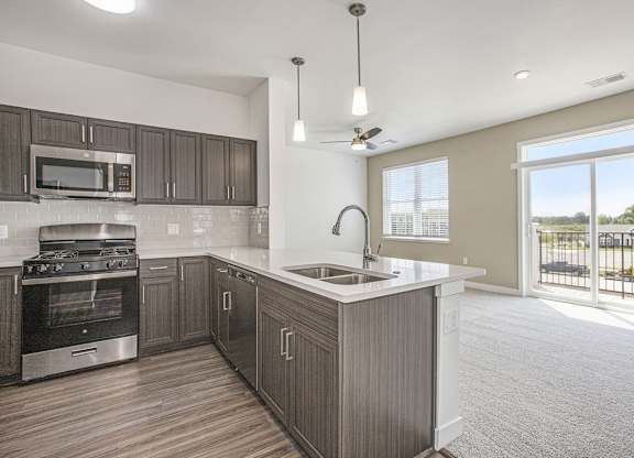 A modern kitchen with dark wood cabinets and stainless steel appliances at Meadowbrooke Apartment Homes in Kentwood, MI 49512