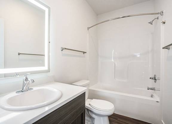 A bathroom with a bathtub/shower combination and a lighted mirror at Meadowbrooke Apartment Homes in Kentwood, MI 49512