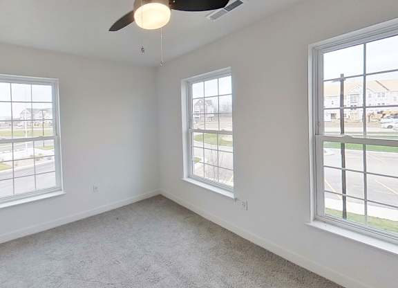 A bedroom with a ceiling fan and three windows at Meadowbrooke Apartment Homes in Kentwood, MI 49512