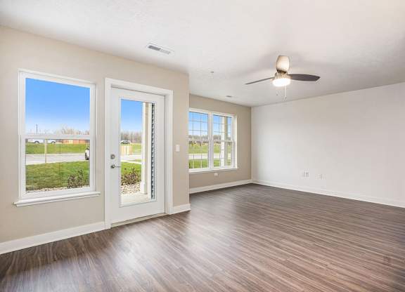 A living room with a ceiling fan and a french door to a private patio at Meadowbrooke Apartment Homes in Kentwood, MI 49512