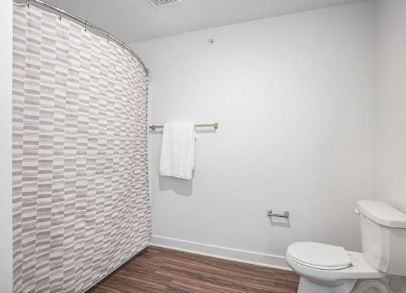 A bathroom with a toilet and a shower curtain at Meadowbrooke Apartment Homes in Kentwood, MI 49512