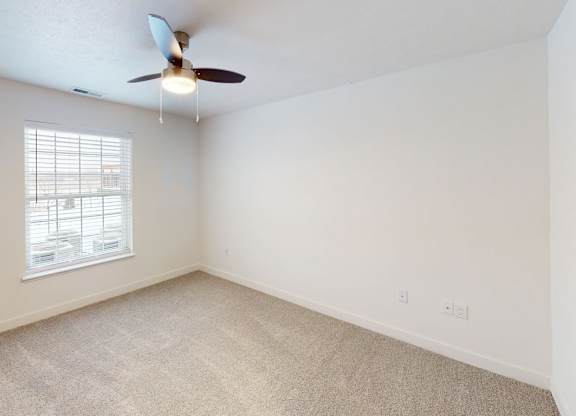 A bedroom with a ceiling fan and a large window with blinds at Meadowbrooke Apartment Homes in Kentwood, MI 49512