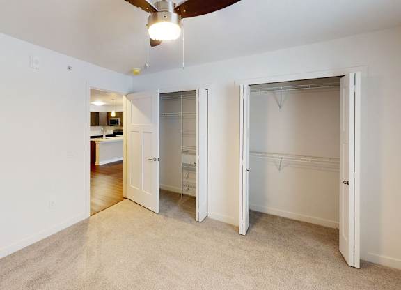 A bedroom with a ceiling fan and two large closets at Meadowbrooke Apartment Homes in Kentwood, MI 49512