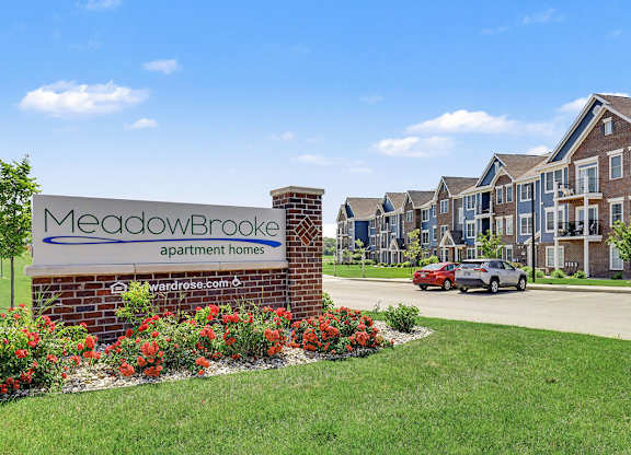 A sign for Meadowbrooke Apartment Homes is in front of a building at Meadowbrooke Apartment Homes in Grand Rapids, MI 49512