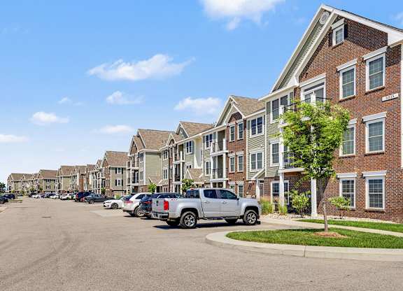 A row of apartment buildings with cars parked in front at Meadowbrooke Apartment Homes in Grand Rapids, MI 49512