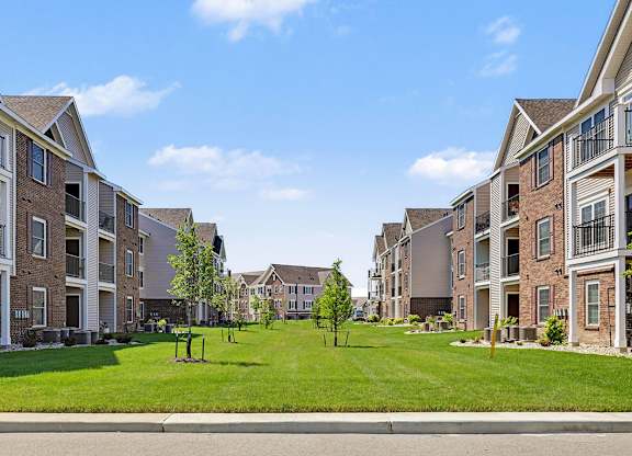 A grassy courtyard between modern apartment buildings at Meadowbrooke Apartment Homes in Grand Rapids, MI 49512