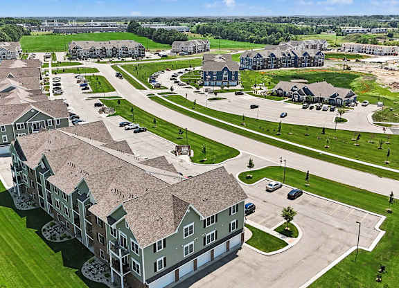 A large, multi-story apartment building with a parking lot in front at Meadowbrooke Apartment Homes in Grand Rapids, MI 49512