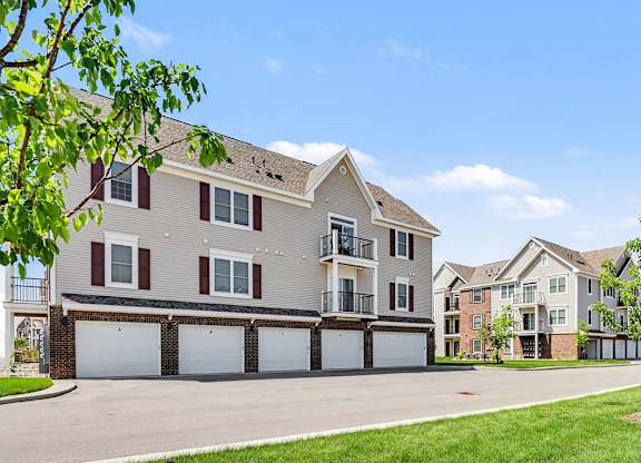 A large apartment building with garages underneath and balconies at Meadowbrooke Apartment Homes in Grand Rapids, MI 49512