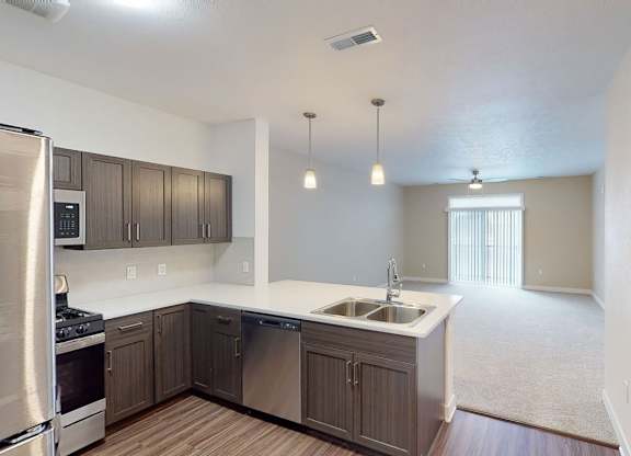 A kitchen overlooking a living room at Meadowbrooke Apartment Homes in Kentwood, MI 49512