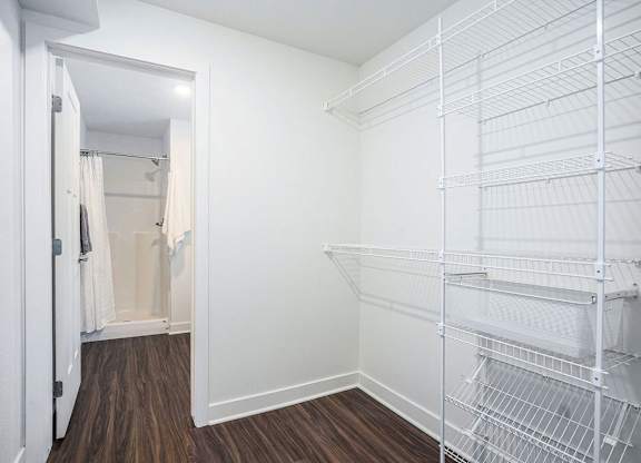 A walk-in closet with wardrobe organizers and a doorway leading to a bathroom at Meadowbrooke Apartment Homes in Kentwood, MI 49512