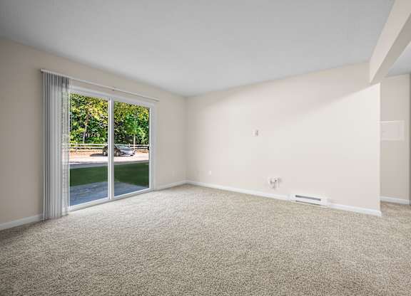 A room with a carpeted floor and a sliding glass door leading to a patiok at Timberlane Apartments, Peoria, Illinois