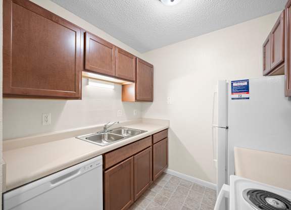 A small kitchen with a white dishwasher and a white refrigeratork at Timberlane Apartments, Peoria, Illinois