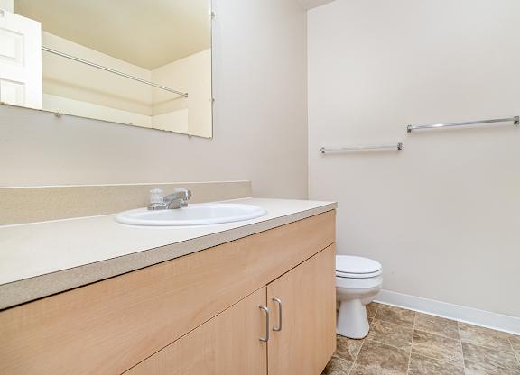 A bathroom with a toilet, sink, and a mirror at Mount Royal Townhomes, Michigan