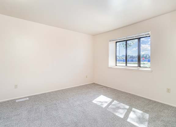 A bedroom with a large window and a carpeted floor at Mount Royal Townhomes, Michigan