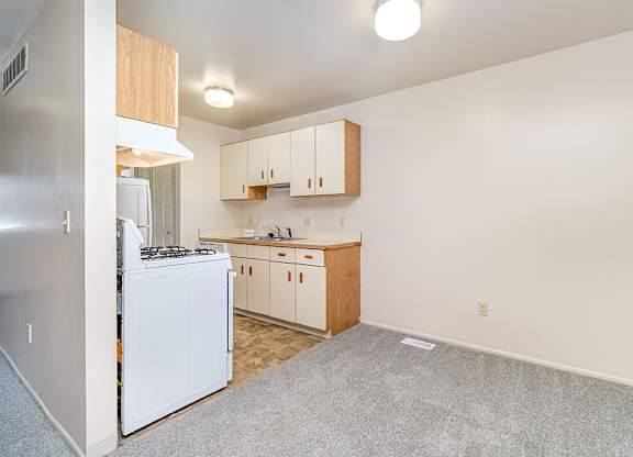A dining room and kitchen with white appliances and wooden cabinets at Mount Royal Townhomes, Michigan