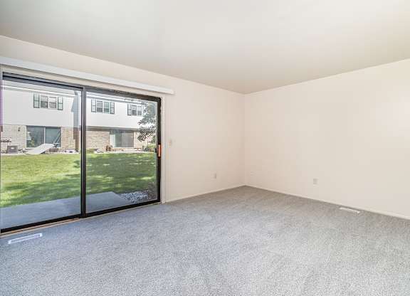 A living room with grey carpet and sliding glass doors to a patio at Mount Royal Townhomes, Michigan