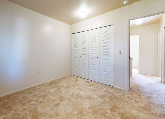 A bedroom with a carpeted floor and a closet at Mount Royal Townhomes, Kalamazoo, MI