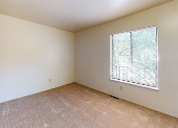 Empty bedroom with a large window and carpeted floor at Mount Royal Townhomes, Michigan